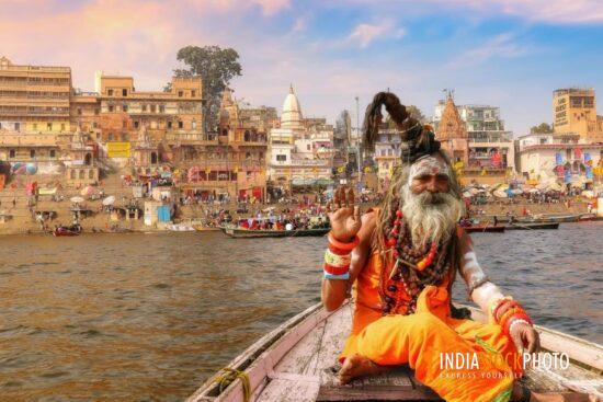 Hindu sadhu on boat ride at Varanasi with view of ancient city architecture