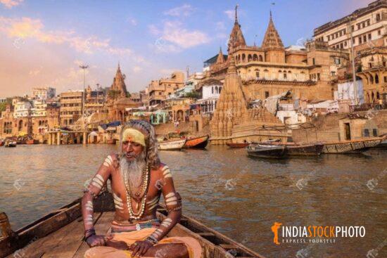 Indian sadhu on a boat at Varanasi with view of ancient city architecture