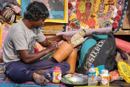 Local artist painting on a handicraft item for sale at a city fair at Kolkata