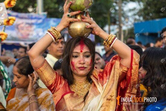 Married woman holding pitcher on her head as part of Durga Puja ritual