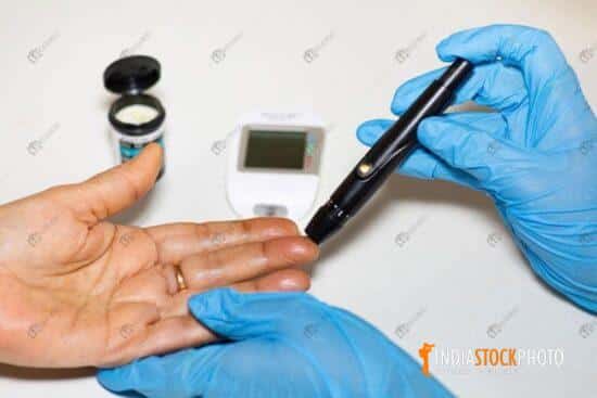 Medical examiner taking blood sample for blood sugar test