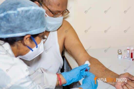 Nurse draws blood sample from an aged Indian male for Covid blood test