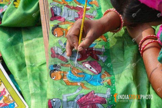 Woman artist hand doing fabric painting on women dress material