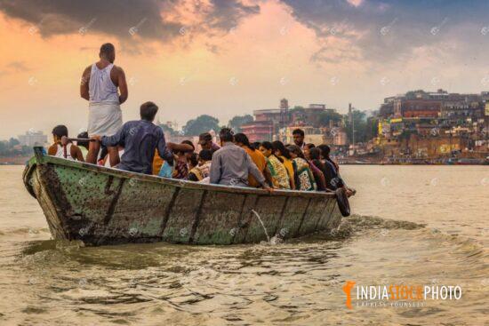 Tourists enjoy boat ride at Varanasi Ganges river at sunset