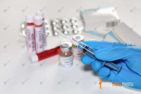 Doctor hand holding injection syringe with blood sample vials and vaccine bottles