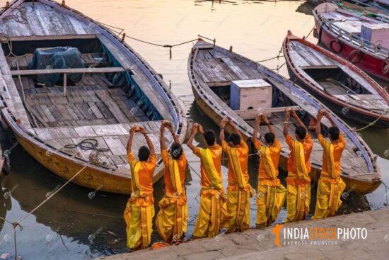 Hindu priests offer prayer at Varanasi Ganges riverbank at dawn