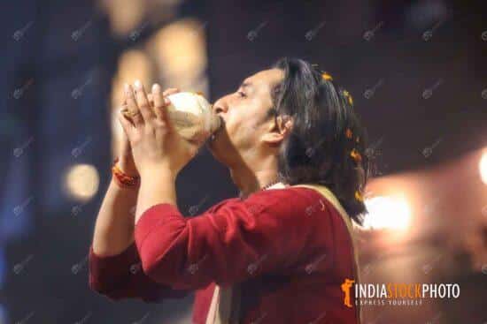 Hindu priest blowing conch shell at Varanasi Ganga aarti