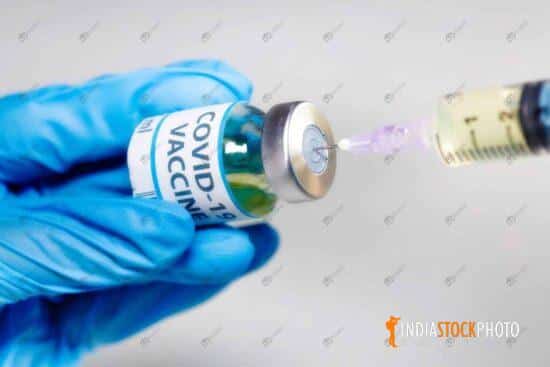 Injection syringe with Covid-19 vaccine bottle in close up