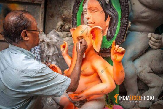 Artist idol maker applying final touches on Ganesh idol