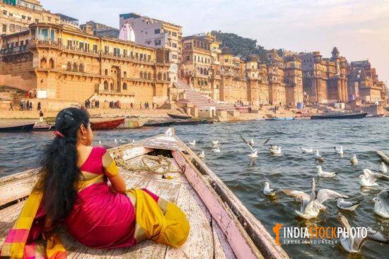Female tourist enjoy boat ride at Varanasi Ganges with migratory birds