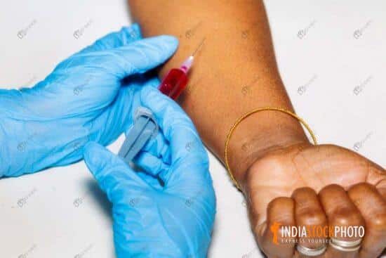 Doctor draws blood sample from Indian patient