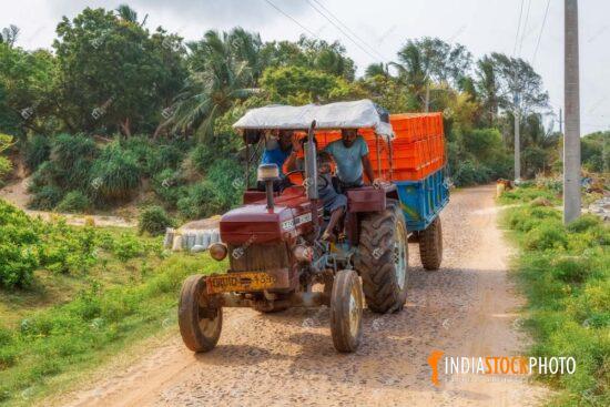 Farmers drive tractor on village road