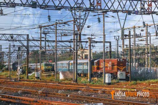 Railway tracks with overhead electrical cable and Indian railway coaches