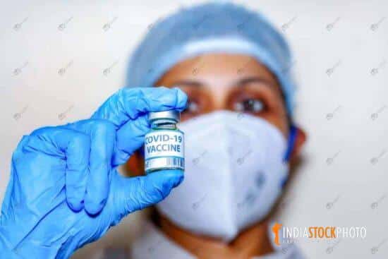 Indian nurse hold a covid-19 vaccine bottle