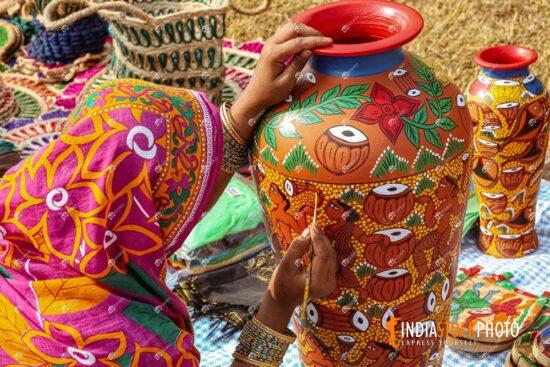 Rural Indian woman artist painting a clay pitcher