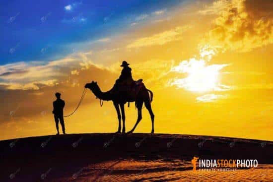 Tourist on desert camel ride in silhouette at sunset at Jaisalmer