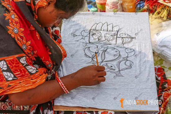 Woman artist performing artwork on dress materials at handicraft item