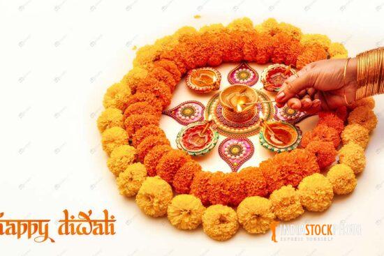 Diwali festival flower Rangoli with woman hand lighting Diya