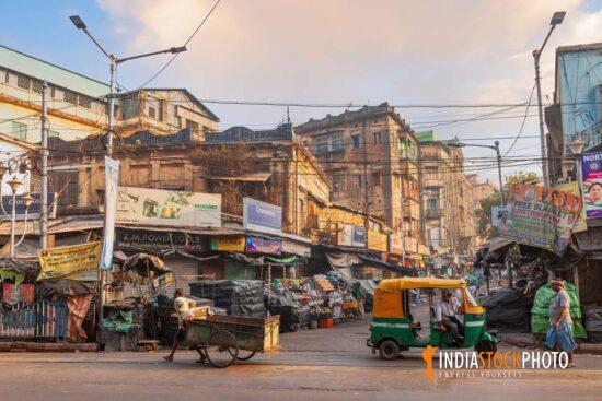 Old city market with roadside shops and vehicles at Kolkata