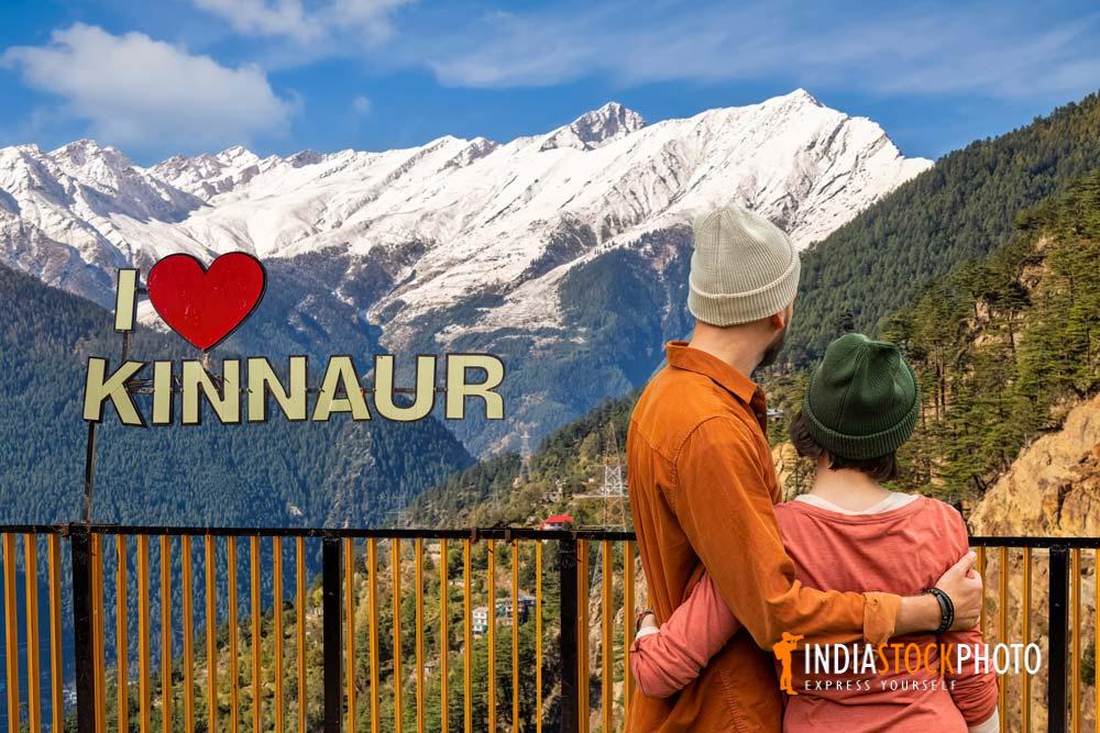 Tourist couple enjoy scenic Kinnaur Kailash Himalaya range at Kalpa Himachal Pradesh